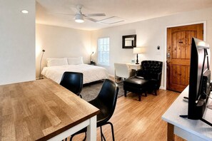 A hotel room with a bed, a desk, a chair, a television, and a wooden door. - Private Cozy Retreat,1GB Fiber WiFi, Near Downtown (Austin)