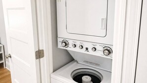 En kompakt, vit tvätt- och torkmaskin som monteras på väggen och har flera justeringsknappar och inställningsmöjligheter.