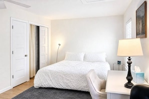 A hotel room with a bed, a desk, a chair, a lamp, and a painting on the wall. - King•Heart of East Downtown•Self Check-In (Austin)