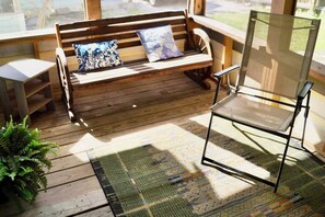 A wooden bench with cushions, a metal chair, and a patterned rug on a wooden deck. - Private Cozy Retreat,1GB Fiber WiFi, Near Downtown (Austin)