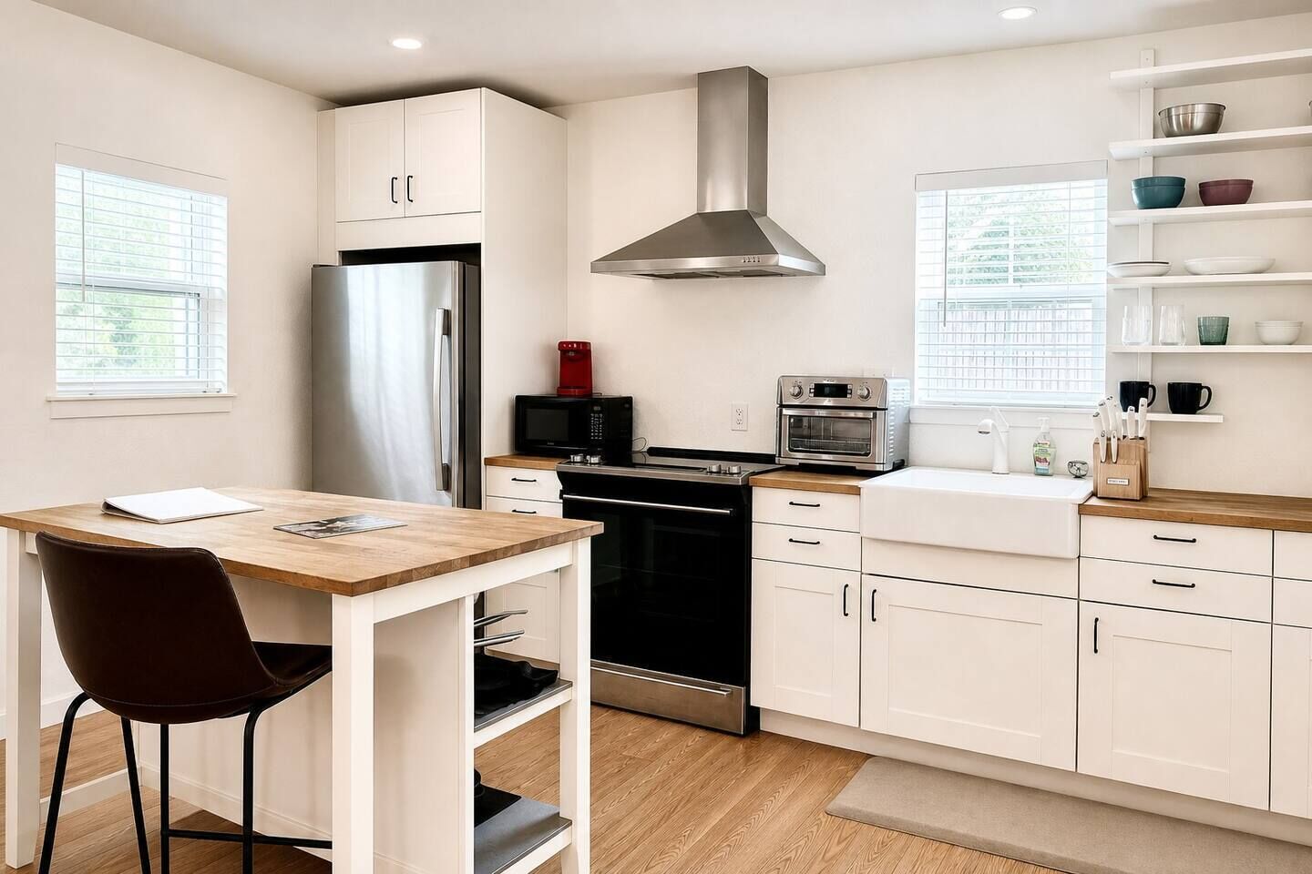 A modern kitchen with white cabinetry, stainless steel appliances, and a wooden dining table.
