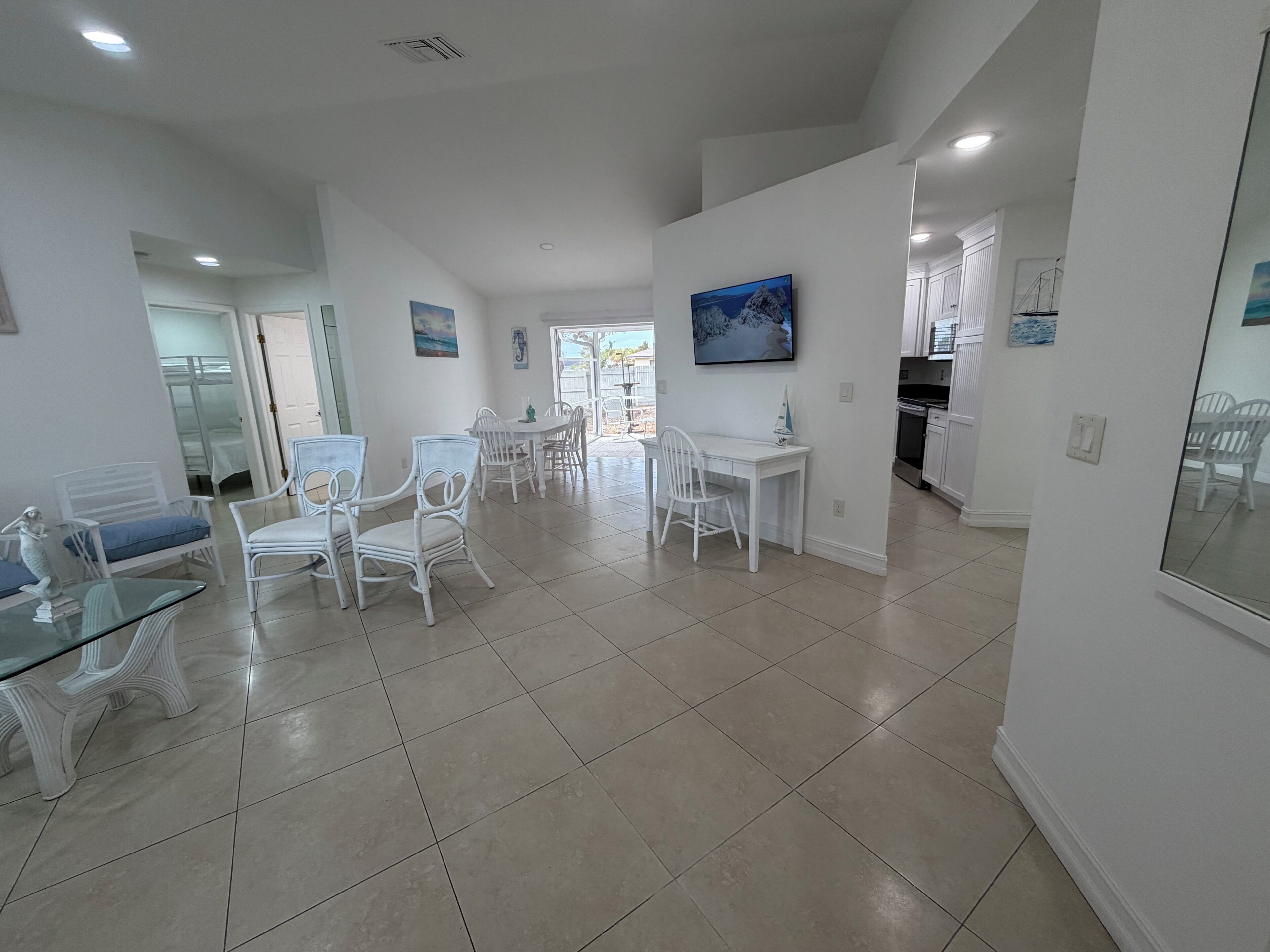 Amplia sala de estar con mesa y sillas de comedor, zona de cocina y vistas a través de una puerta abierta.
