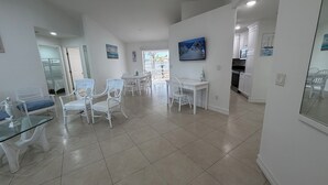 A spacious living area with a dining table and chairs, a kitchen area, and a view through an open door.