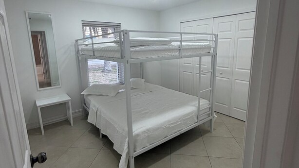 A bunk bed room with a mirror, a small table, and a wardrobe.