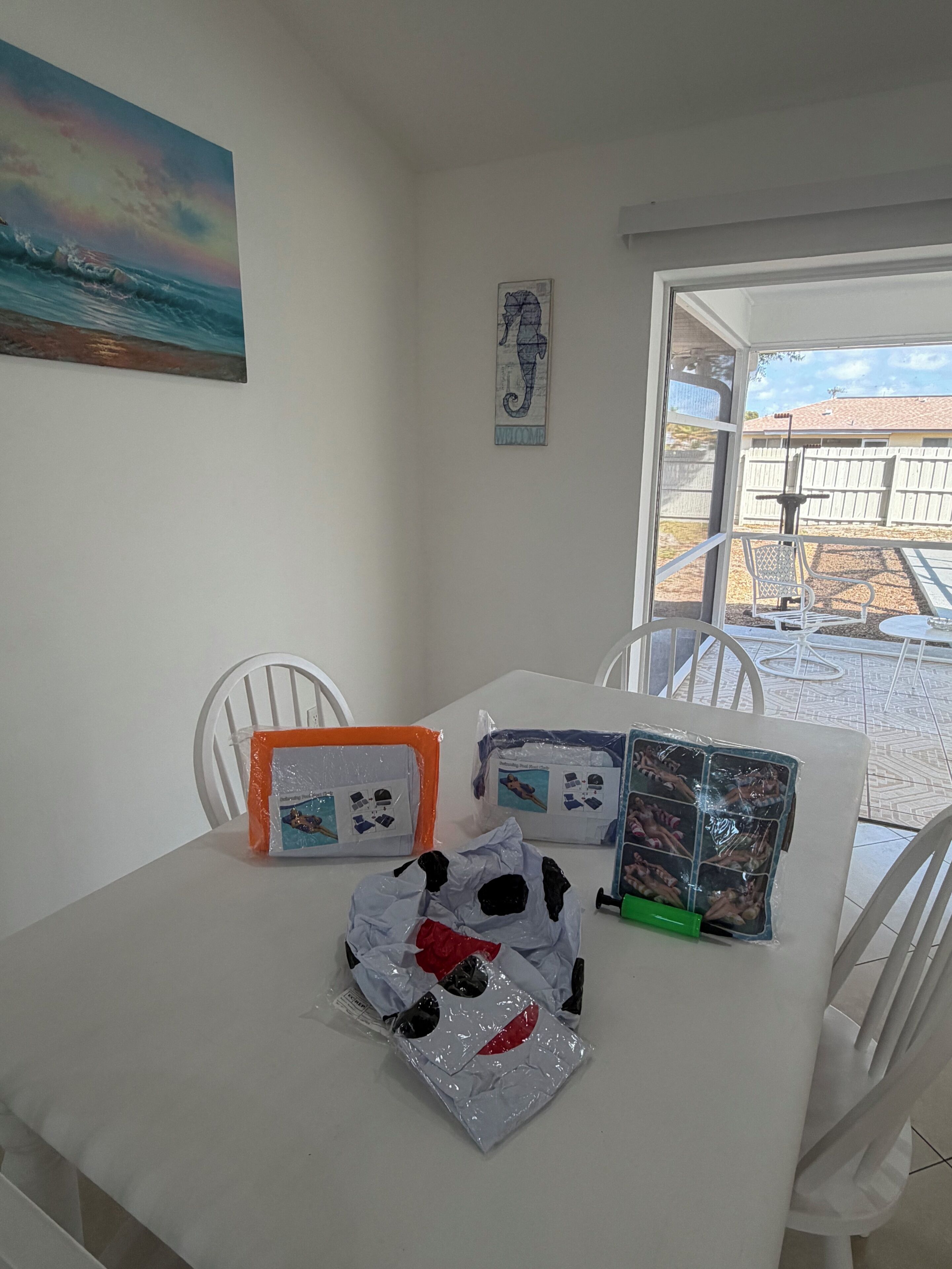 Un comedor con una mesa dispuesta para dos personas, sillas, un cuadro en la pared y vistas al jardín trasero.