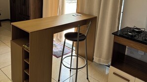 A compact kitchen with a wooden countertop, a gas stove, a single chair, and a cabinet. - Cozy kitchenette (Araçuaí)