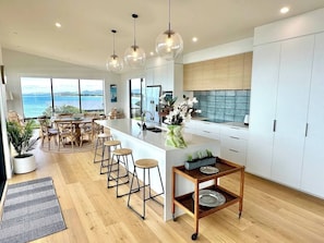 A modern kitchen with a large island, bar stools, and a view of the ocean.