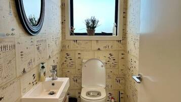 A bathroom with a window, a sink, and a toilet.