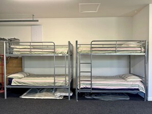A room with two bunk beds, a red ladder, and a door in the background. - Coastal Luxe Villa Kakanui (Kakanui)