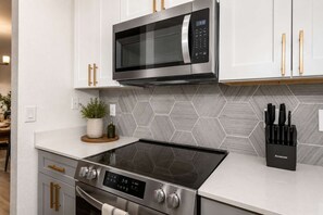 A modern kitchen with a stainless steel microwave, a built-in oven, and a stovetop. - Scottsdale Retreat - 2BR Resort Condo with pool and Gym (Scottsdale)