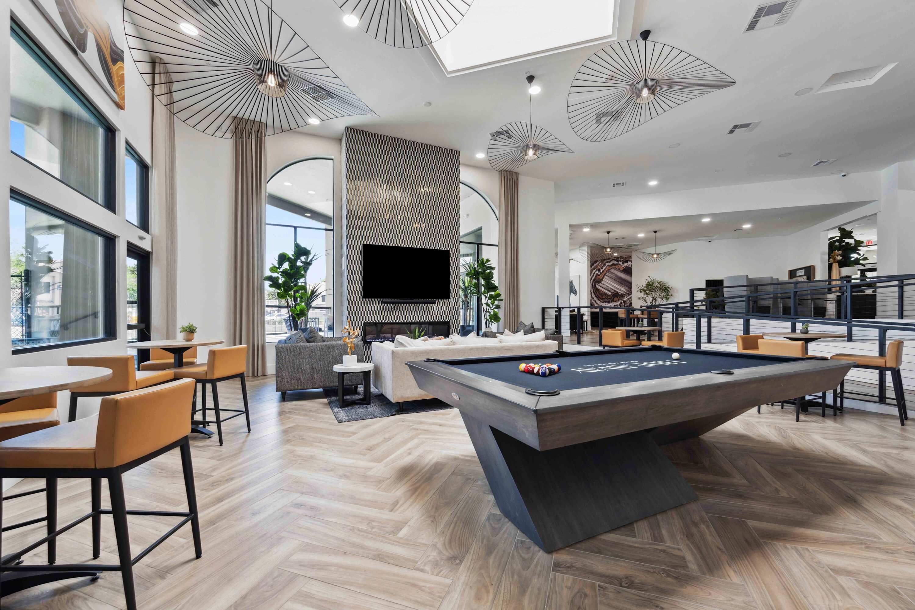 A modern interior with a pool table, seating area, and a large flat-screen TV.