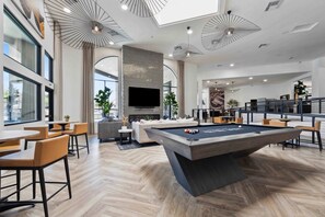 A modern interior with a pool table, seating area, and a large flat-screen TV. - Stylish 2BR Retreat w Pool and Gym (Scottsdale)