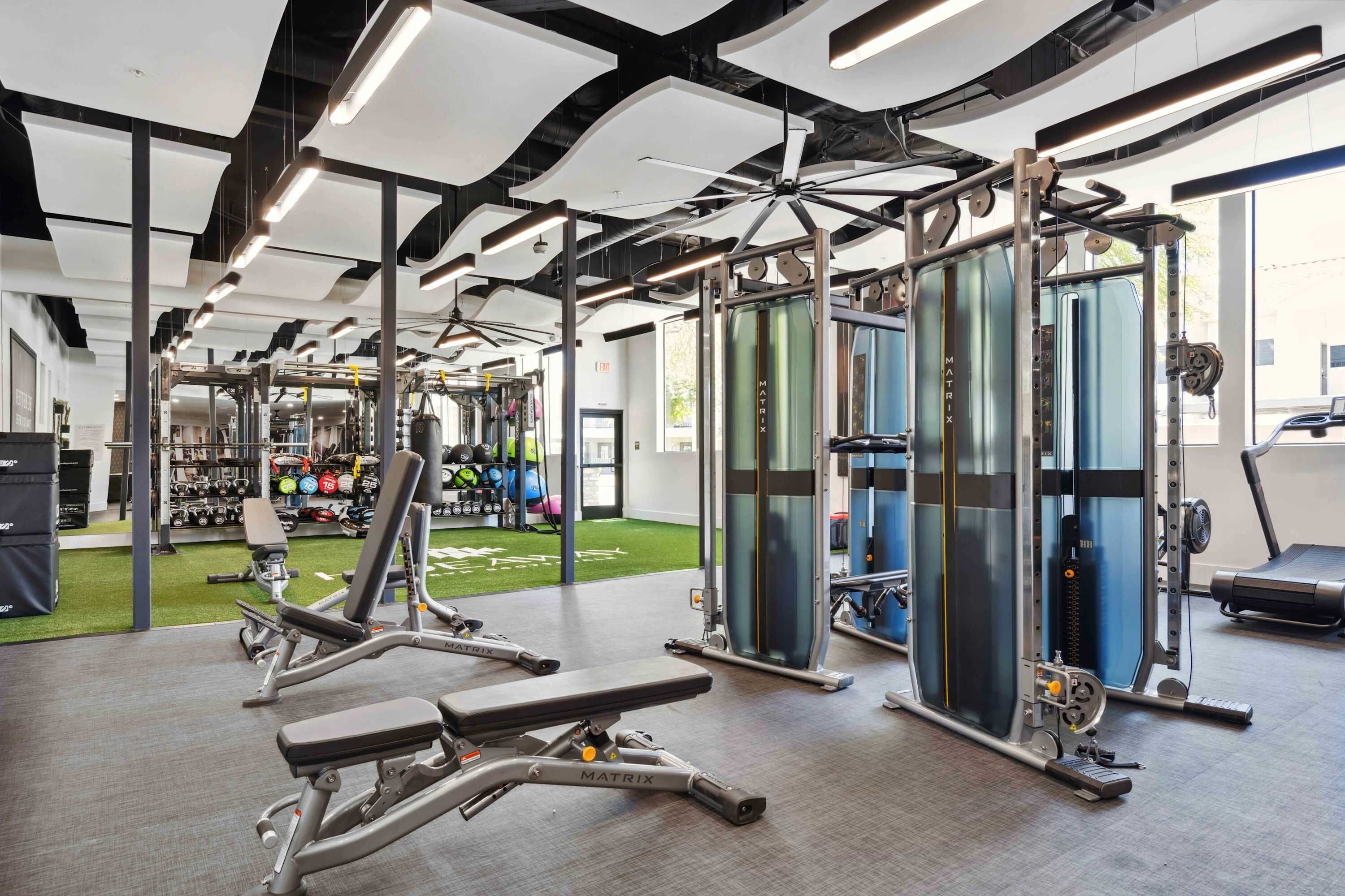 Een sportschool met diverse fitnessapparaten, waaronder krachtapparaten en losse gewichten.