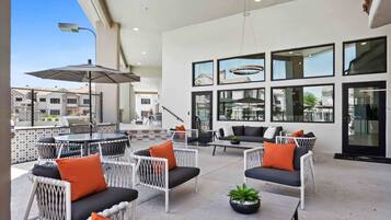 Un patio al aire libre con disposición de asientos, una parrilla y vistas de la ciudad.