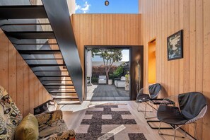 A modern interior with a staircase, seating area, and a view to an outdoor space. - The Sumner Escape - Sleeps 5, Walk to Beach (Christchurch)