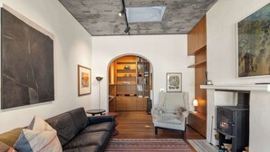 Ein modernes Wohnzimmer mit einer Ledersofa, einem gemusterten Teppich, einem Kamin und einem Bücherregal.