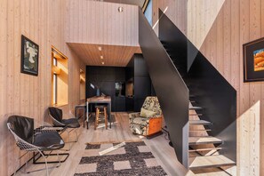 A modern interior with a wooden floor, a staircase, and a dining area with chairs and a table. - The Sumner Escape - Sleeps 5, Walk to Beach (Christchurch)