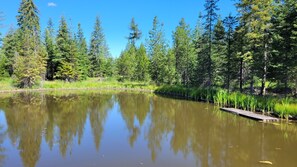 A calm lake with a wooden dock extending into the water, surrounded by dense forest. - The Duck is a fully stocked camper, perfect for hunting camp or young families (Deary)
