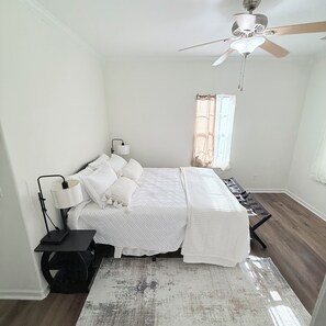 A bedroom with a bed, bedside lamps, a ceiling fan, and a window with curtains. - Beautifully Renovated 3-Bedroom Home Minutes from Downtown Atlanta (Atlanta)