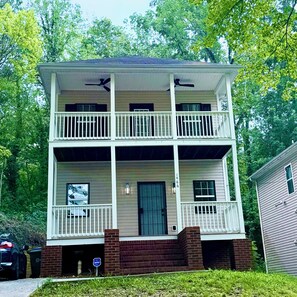 A two-story building with a front porch, a central door, and a small attached garage. - Beautifully Renovated 3-Bedroom Home Minutes from Downtown Atlanta (Atlanta)