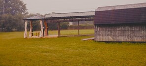 A wooden structure with a covered seating area and a separate building.