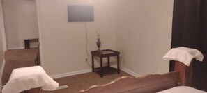A bedroom with a bed, a small table, and a wall-mounted TV.