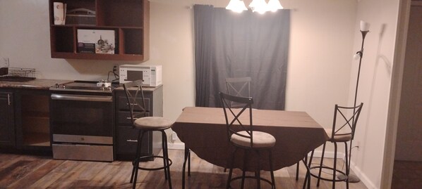 A compact kitchen with a microwave, oven, and a dining area with a table and two chairs.