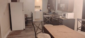 A compact kitchen with a refrigerator, microwave, and a dining area with chairs.
