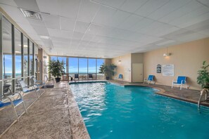 An indoor swimming pool with clear views of the ocean, lounge chairs, and a poolside area. - Luxury 4 BR Beachfront Condo - Admirals Quarters 601A - Indoor Outdoor Pool (Orange Beach)