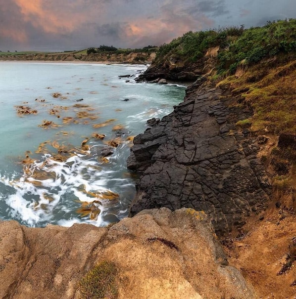 A coastal landscape with rocky terrain and waves crashing against the shore.