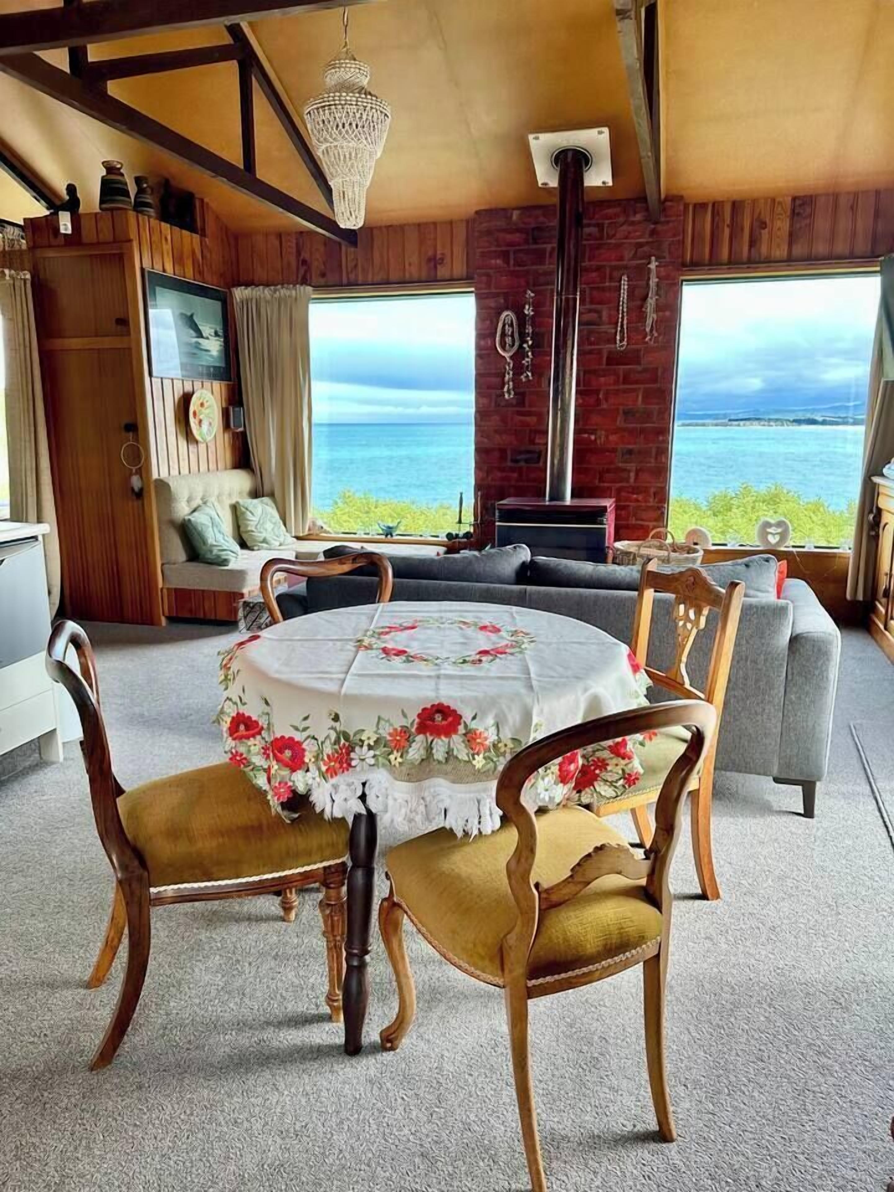 A dining area with a round table, floral tablecloth, and wooden chairs.