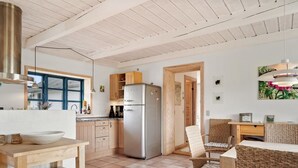 Una cocina moderna con un refrigerador de acero inoxidable, armarios de madera y un comedor con sillas de mimbre.