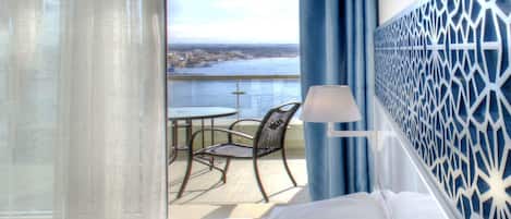 Une chambre d’hôtel avec un lit, une chaise, une table et une vue sur la mer.