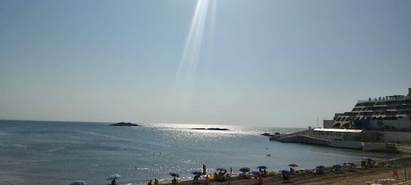 A beach with a pier, umbrellas, and a clear sky.