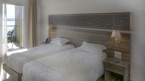 Een hotelkamer met twee bedden, een balkon met een stoel en een decoratief wandpaneel.