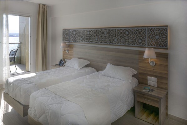 A hotel room with two beds, a balcony with a chair, and a decorative wall panel.