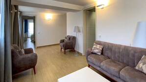 Een moderne woonkamer met een bank, twee fauteuils, een salontafel en een lamp.