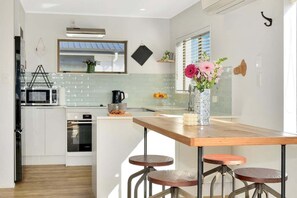 Eine moderne Küche mit weißen Schränken, einer Holzeile mit Sitzgelegenheiten, einer Mikrowelle und einer Vase mit Blumen.