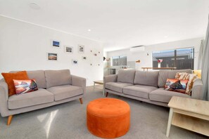 Ein modernes Wohnzimmer mit zwei Sofas, einem runden Hocker und einem kleinen Tisch.