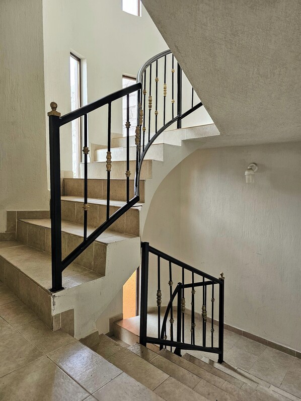 A staircase with a black handrail and balusters, leading to an upper floor.