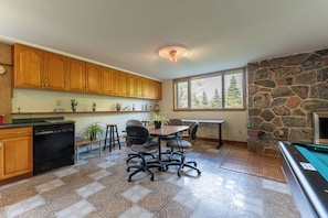 A kitchen with wooden cabinets, a dining table with chairs, a dishwasher, and a stone fireplace.