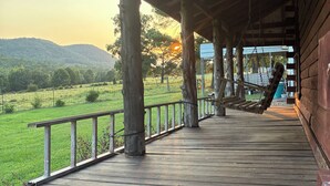 Um deck de madeira com vista para um campo verde e colinas ao longe.