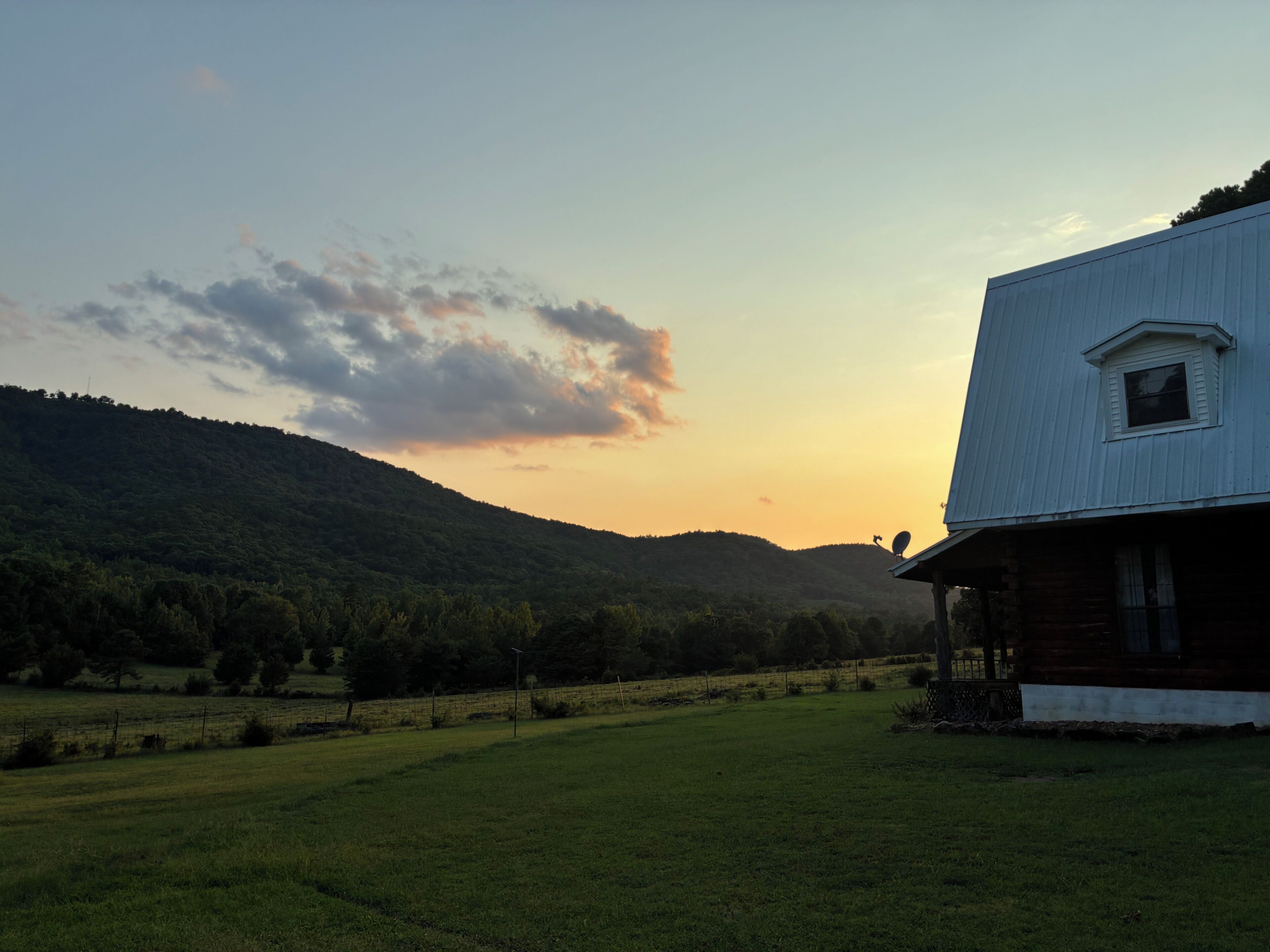 Ländliche Landschaft mit einem Haus, das durch seine auffällige weiße Fassade und ein kleines Fenster gekennzeichnet ist.