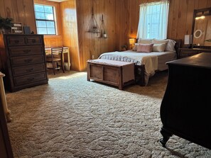 Ein gemütliches Schlafzimmer mit Holzboden, einem Himmelbett, einem Schminktisch und einem Schreibtisch mit Stuhl.