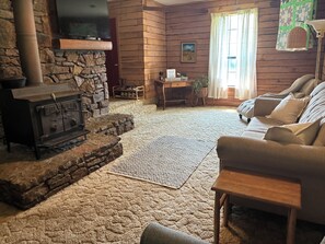 A cozy living room with a stone fireplace, a sofa, and a television.