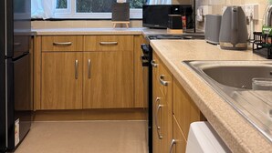 Une cuisine moderne avec des meubles en bois, un four encastré, un four à micro-ondes et un lave-vaisselle.