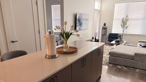 Een moderne keuken met een centraal eiland, een zithoek met een bank en een woonkamer met een televisie.