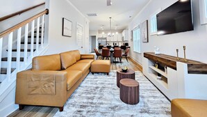 En moderne stue med sofa, sofabord og et fjernsyn monteret på væggen.