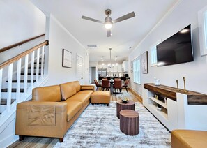Ein modernes Wohnzimmer mit einer Couch, einem Couchtisch und einem an der Wand befestigten Fernseher.