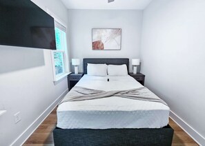 A bedroom with a bed, two bedside tables, a wall-mounted TV, and a framed artwork. - 7 Min to Duke + Downtown | Free Parking (Durham)
